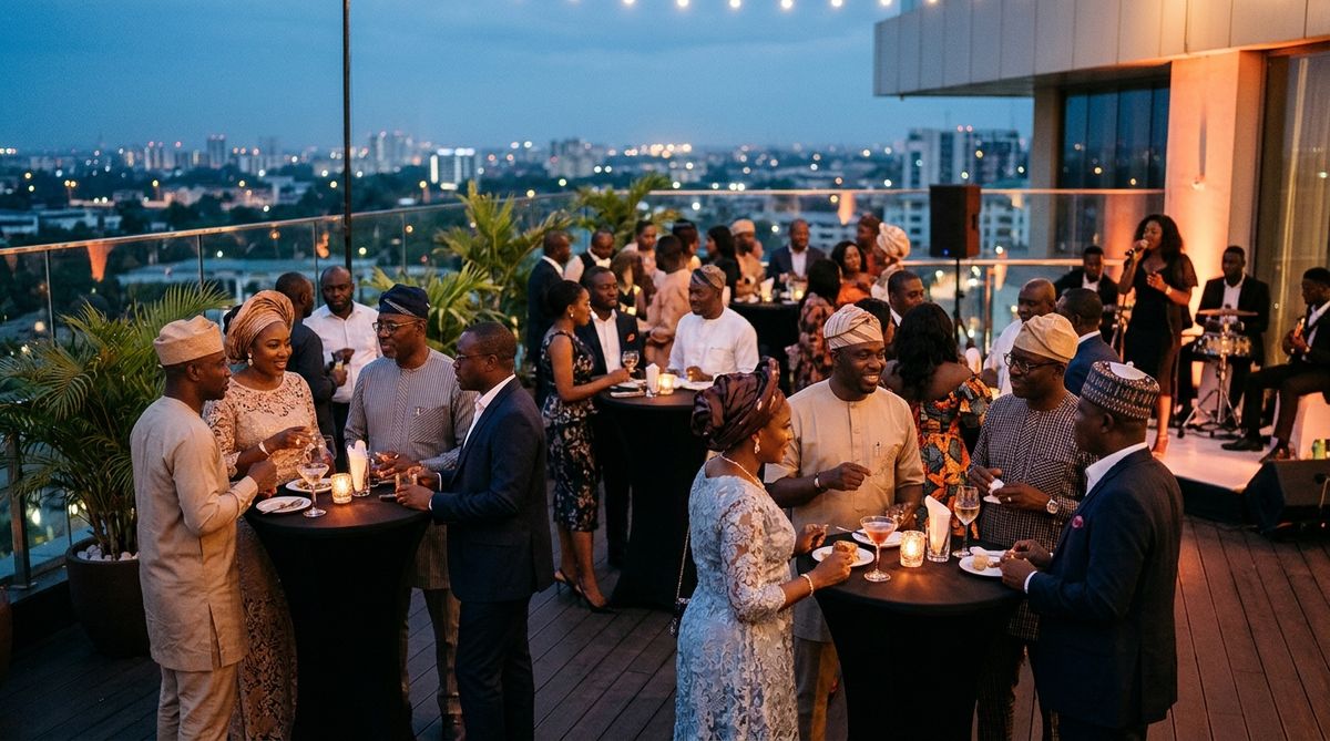 Colleagues networking over drinks on a hotel rooftop terrace as the city lights come on at dusk.